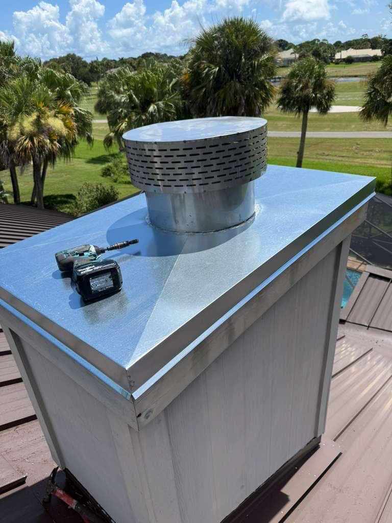 Round vented cap and broad metal chimney cover, with a drill resting on top.