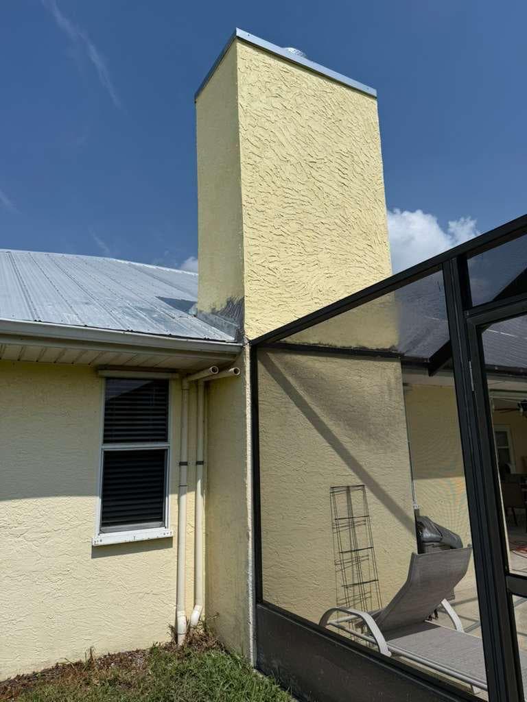 Tall yellow-finished chimney enclosure beside a screened patio.